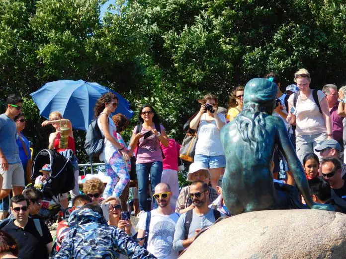 Die kleine Meerjungfrau in Kopenhagen von hinten, davor ganz viele Menschen